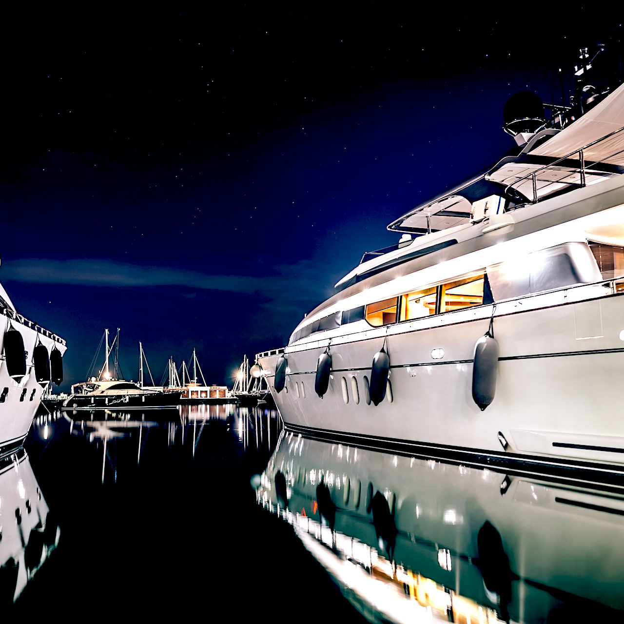 Luxury yachts in La Spezia harbor at night with reflection in water. Italy